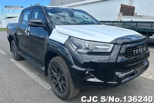 Black Toyota pickup with dented white hood cover, front bumper and fender damage, parked in a lot; crew cab and alloy wheels visible.